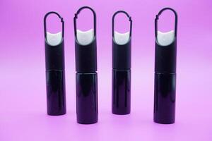 mini sprayer bottles isolated on purple background. four sprayer bottles with hangers photo