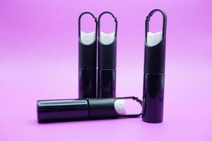mini sprayer bottles isolated on purple background. four sprayer bottles with hangers photo