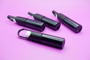 mini sprayer bottles isolated on purple background. four sprayer bottles with hangers photo