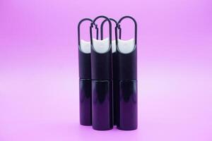 mini sprayer bottles isolated on purple background. four sprayer bottles with hangers photo