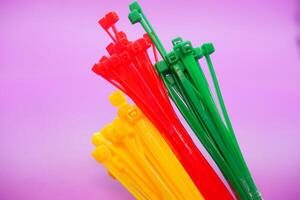 bundle of zip ties isolated on purple background. zip ties in red, green, and yellow. Cable ties or cable ties, straps that can be used for various purposes. photo