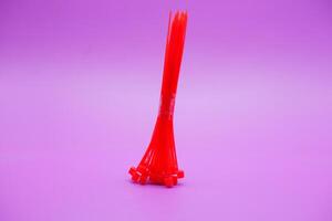 bundle of red zip ties isolated on purple background. Cable ties or cable ties, straps that can be used for various purposes. photo
