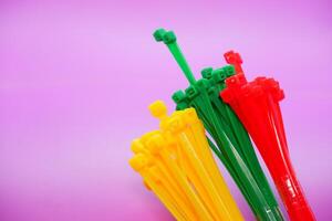bundle of zip ties isolated on purple background. zip ties in red, green, and yellow. Cable ties or cable ties, straps that can be used for various purposes. photo
