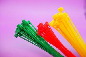bundle of zip ties isolated on purple background. zip ties in red, green, and yellow. Cable ties or cable ties, straps that can be used for various purposes. photo