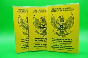 international certificate of vaccination or prophylaxis isolated on green background. 3 yellow books as a sign of vaccination. yellow book of vaccines from indonesia photo