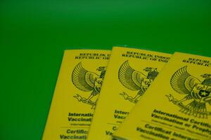 international certificate of vaccination or prophylaxis isolated on green background. 3 yellow books as a sign of vaccination. yellow book of vaccines from indonesia photo