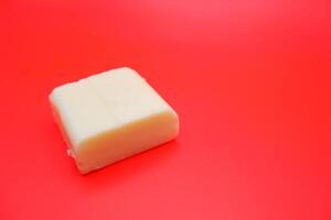 cube shaped cheese isolated on red background. mozzarella cheese that melts easily photo
