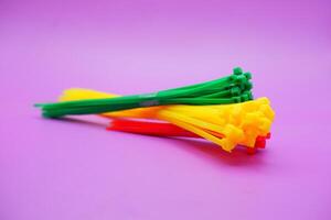 bundle of zip ties isolated on purple background. zip ties in red, green, and yellow colors arranged in a stacked manner. Cable ties or cable ties, straps that can be used for various purposes. photo