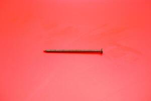 rusty nail isolated on red background. rusty nail with a length of approximately 10 cm photo