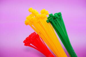 bundle of zip ties isolated on purple background. zip ties in red, green, and yellow. Cable ties or cable ties, straps that can be used for various purposes. photo