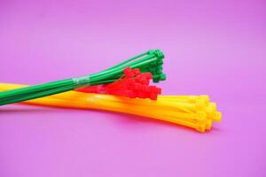 bundle of zip ties isolated on purple background. zip ties in red, green, and yellow colors arranged in a stacked manner. Cable ties or cable ties, straps that can be used for various purposes. photo