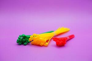 bundle of zip ties isolated on purple background. zip ties in red, green, and yellow colors arranged in a row. Cable ties or cable ties, straps that can be used for various purposes. photo