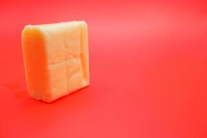 cube shaped cheese isolated on red background. mozzarella cheese that melts easily photo