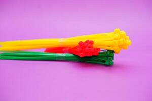 bundle of zip ties isolated on purple background. zip ties in red, green, and yellow colors arranged in a stacked manner. Cable ties or cable ties, straps that can be used for various purposes. photo