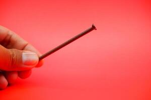 rusty nail isolated on red background. rusty nail with a length of approximately 10 cm photo