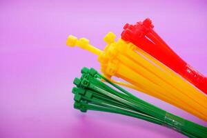 bundle of zip ties isolated on purple background. zip ties in red, green, and yellow. Cable ties or cable ties, straps that can be used for various purposes. photo