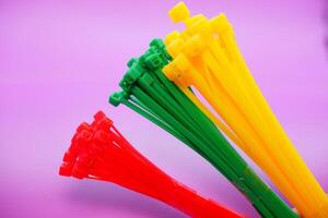 bundle of zip ties isolated on purple background. zip ties in red, green, and yellow. Cable ties or cable ties, straps that can be used for various purposes. photo