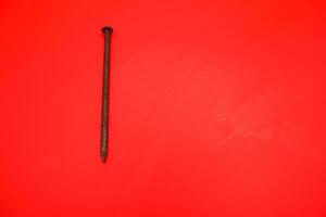 rusty nail isolated on red background. rusty nail with a length of approximately 10 cm photo