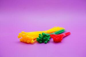 bundle of zip ties isolated on purple background. zip ties in red, green, and yellow colors arranged in a row. Cable ties or cable ties, straps that can be used for various purposes. photo