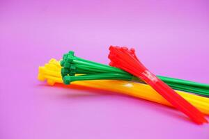 bundle of zip ties isolated on purple background. zip ties in red, green, and yellow colors arranged in a stacked manner. Cable ties or cable ties, straps that can be used for various purposes. photo