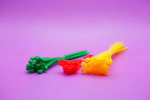 bundle of zip ties isolated on purple background. zip ties in red, green, and yellow colors arranged in a row. Cable ties or cable ties, straps that can be used for various purposes. photo