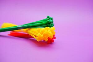 bundle of zip ties isolated on purple background. zip ties in red, green, and yellow colors arranged in a stacked manner. Cable ties or cable ties, straps that can be used for various purposes. photo