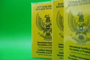 international certificate of vaccination or prophylaxis isolated on green background. 3 yellow books as a sign of vaccination. yellow book of vaccines from indonesia photo
