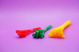 bundle of zip ties isolated on purple background. zip ties in red, green, and yellow colors arranged in a row. Cable ties or cable ties, straps that can be used for various purposes. photo