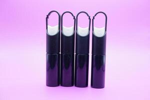 mini sprayer bottles isolated on purple background. four sprayer bottles with hangers photo