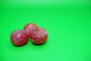 3 grapes isolated on green background. Fresh purple grapes. photo