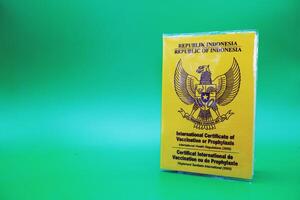 international certificate of vaccination or prophylaxis isolated on green background. yellow book as a sign of vaccination. yellow book of vaccines from indonesia photo