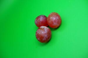 3 grapes isolated on green background. Fresh purple grapes. photo