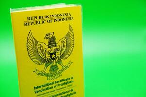 international certificate of vaccination or prophylaxis isolated on green background. yellow book as a sign of vaccination. yellow book of vaccines from indonesia photo