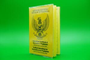 international certificate of vaccination or prophylaxis isolated on green background. yellow book as a sign of vaccination. yellow book of vaccines from indonesia photo