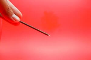rusty nail isolated on red background. rusty nail with a length of approximately 10 cm photo