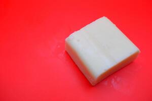 cube shaped cheese isolated on red background. mozzarella cheese that melts easily photo