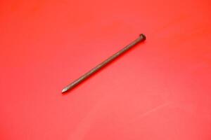rusty nail isolated on red background. rusty nail with a length of approximately 10 cm photo