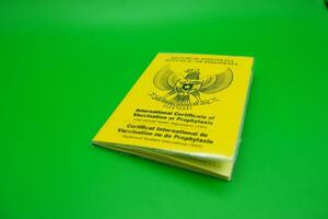 international certificate of vaccination or prophylaxis isolated on green background. yellow book as a sign of vaccination. yellow book of vaccines from indonesia photo