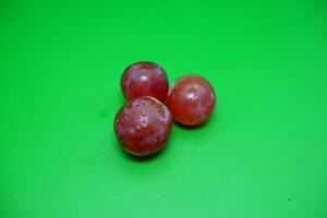 3 grapes isolated on green background. Fresh purple grapes. photo