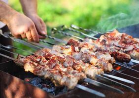 Marinated shashlik, lamb meat grilling on metal skewer, close up photo