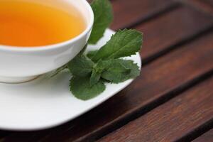 a cup of tea on a saucer with a leaf on it photo