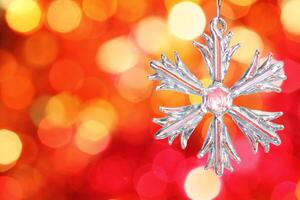 Glass snowflake against red blurred background photo