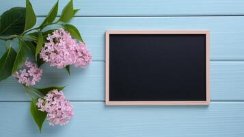 Small blackboard mockup and fresh lilac flowers. Holiday greeting card with spring blossom template advertising image. Chalkboard mock up on blue boards product photorealistic photo