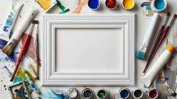Art supplies with white empty frame mockup. Colorful paint tubes, brushes. Artist workspace photoframe template advertising image. Painter tools pictureframe border mock up realistic photo