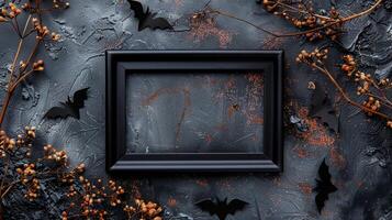Black frame mockup surrounded by bat cutouts and dried branches. Scattered orange glitter Helloween pictureframe template advertising image. Halloween photoframe mock up photorealistic photo