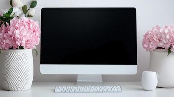 Mockup pc display with hortensias on desk. Festive floral design of office with monitor template advertising image. Spring decor of workplace with device mock up product photorealistic photo