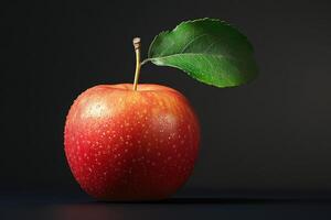 Ripe red apple with a green leaf resting on a dark surface during soft lighting photo