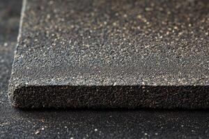 Close-up of textured black sandpaper on a work surface highlighting fine grit and surface detail photo