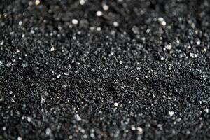Close-up view of fine black sand with sparkling grains scattered across the surface photo