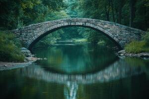 Tranquil stone bridge arching over serene waters in a forested landscape during early morning photo